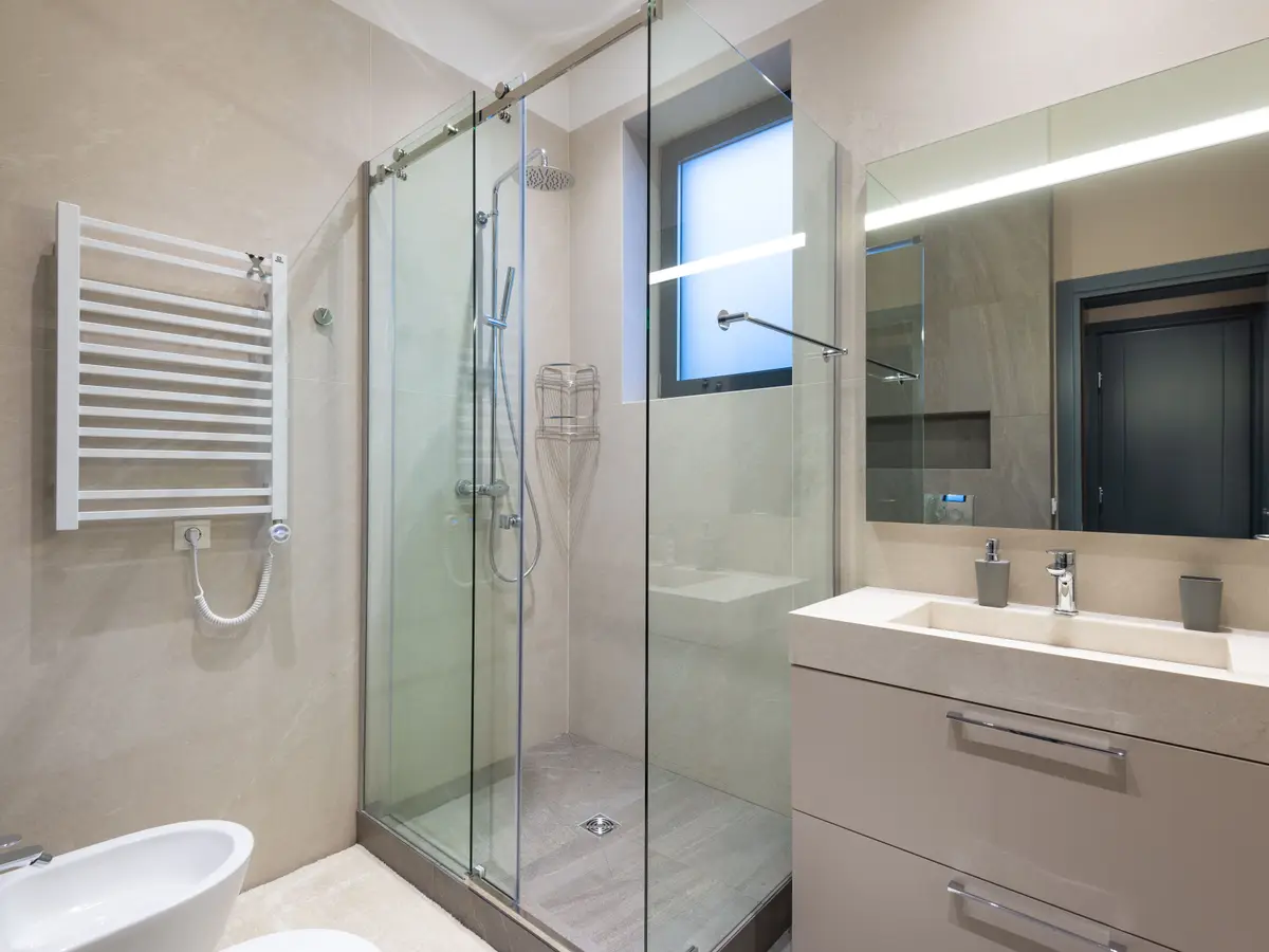 A finished bathroom with a glass walk-in shower, towel rail and wall-hung basin unit