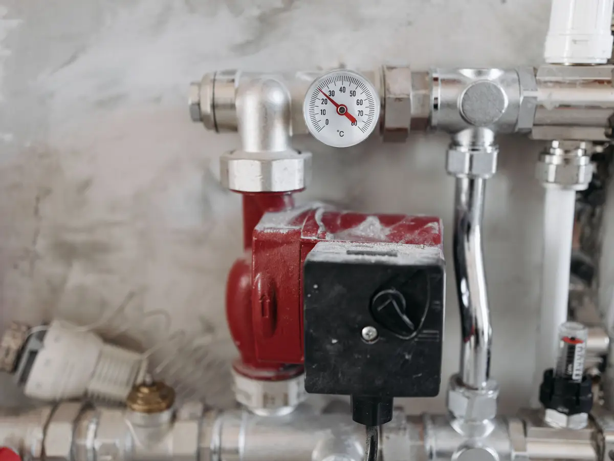 Chrome heating pipework with a red circulating pump and a temperature gauge