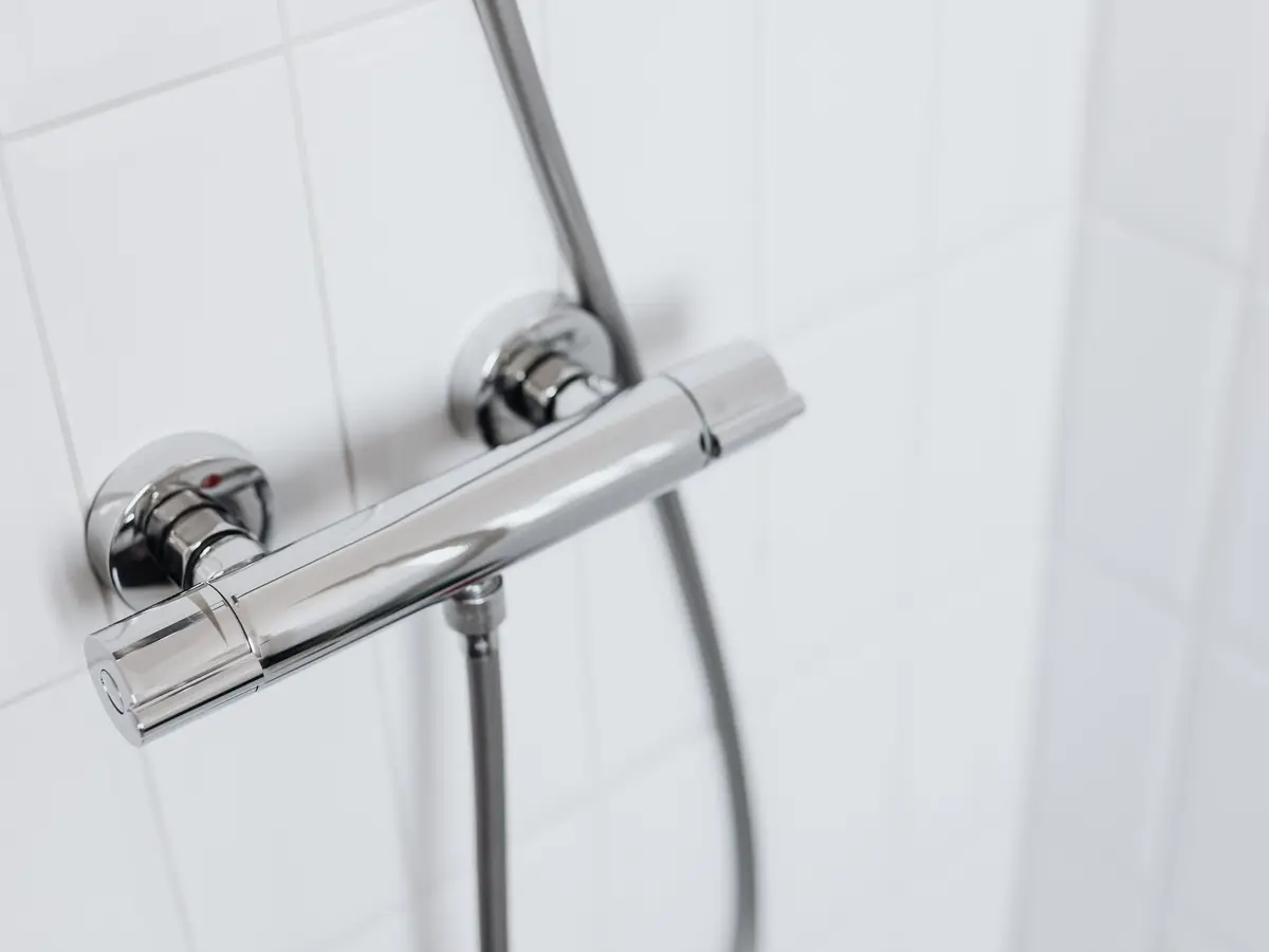 A chrome thermostatic bar shower valve on a white tiled wall