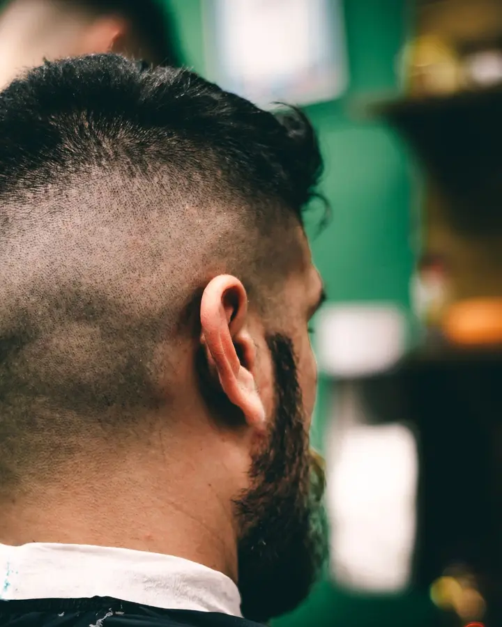 The back of a man's head showing a high fade and a full beard