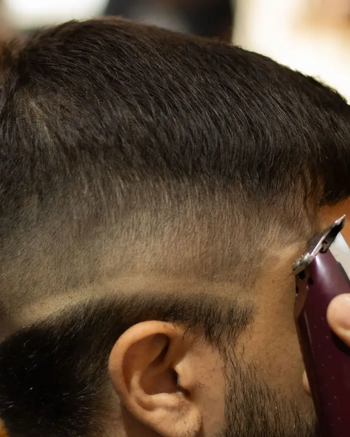 A mid skin fade being blended above a client's ear