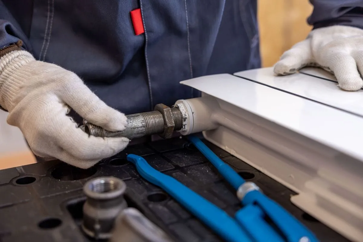 Plumber assembling a radiator pipe fitting with a spanner