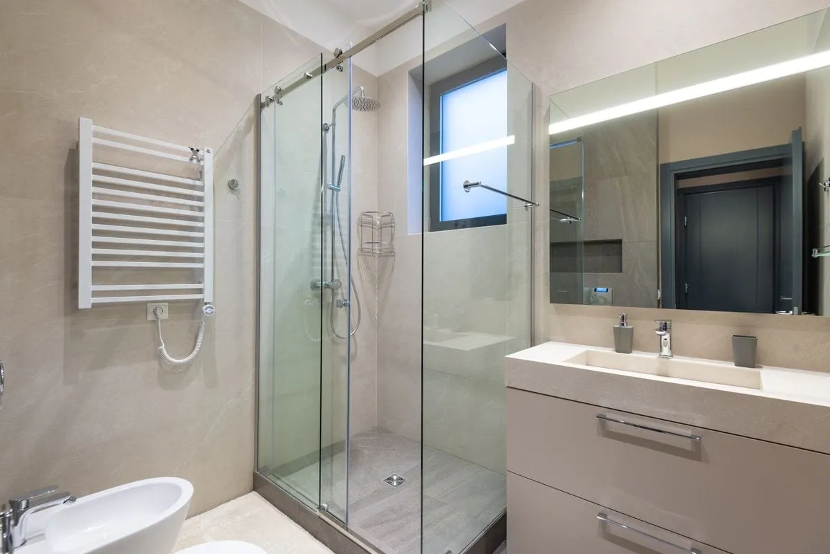 Finished modern bathroom with a glass shower screen and towel radiator