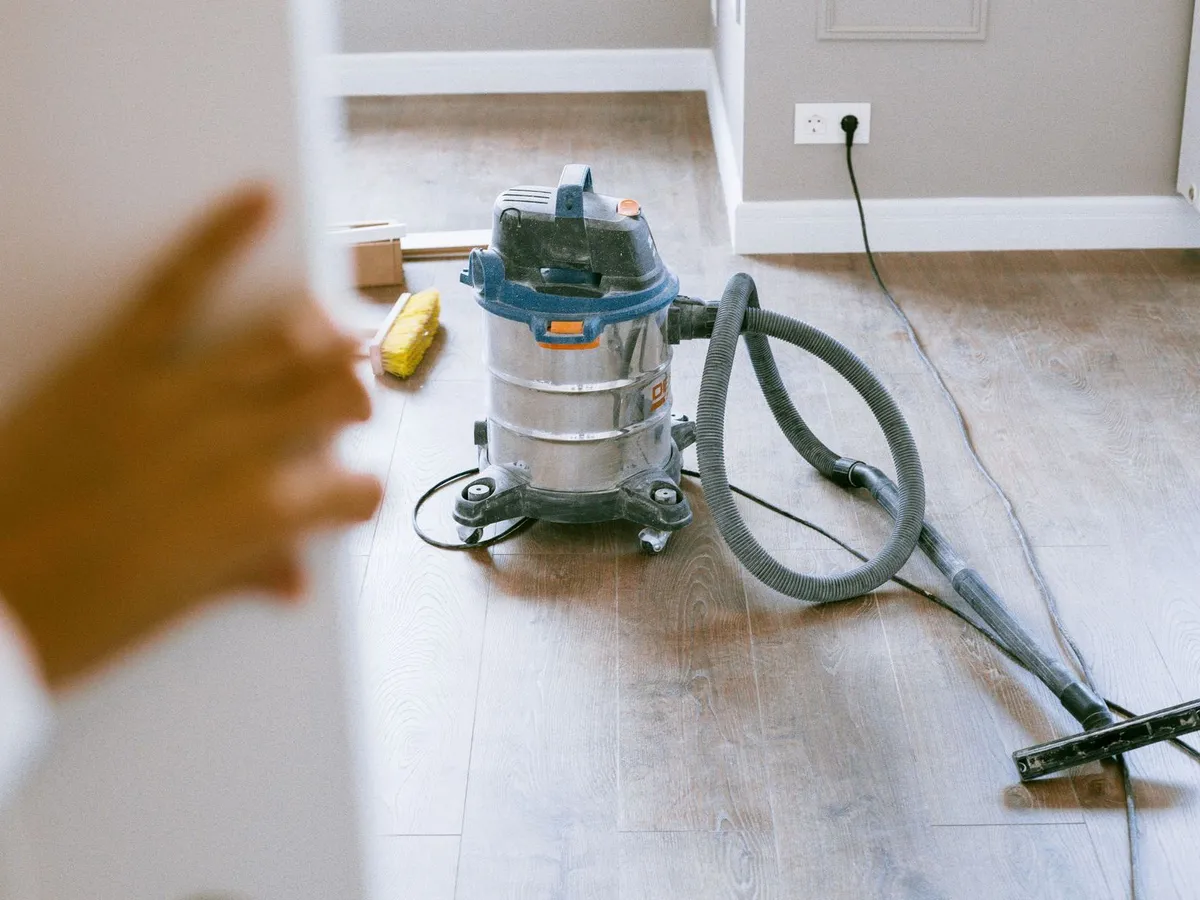 A dust-extracting vacuum cleaner on the new wooden floor of a freshly renovated room