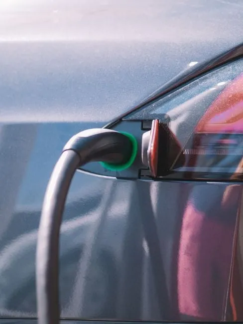 An EV charging cable plugged into an electric car on a driveway