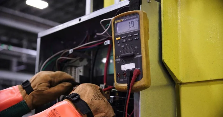 Gloved hands testing an electrical panel with a multimeter